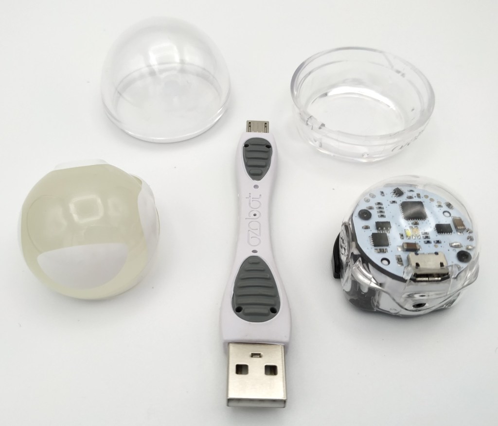 Le robot Ozobot Bit 2.0 avec son câble de rechargement et sa coque de protection
